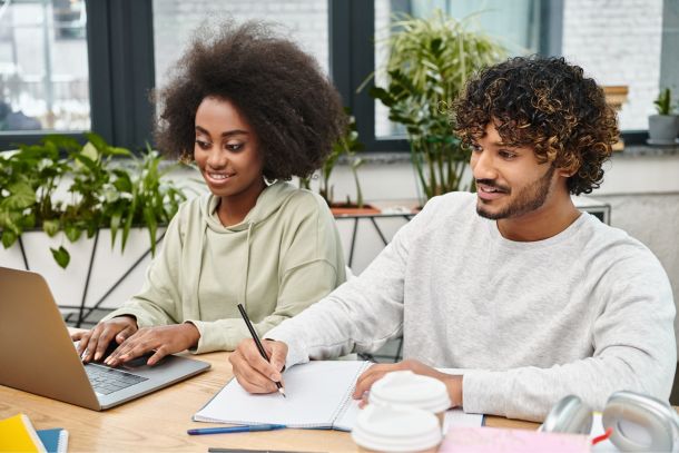 girl and guy viewing laptop while working together