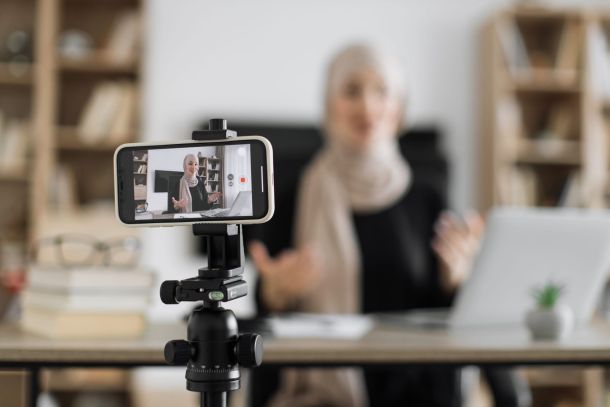 Online female teacher with head covering waiving hand